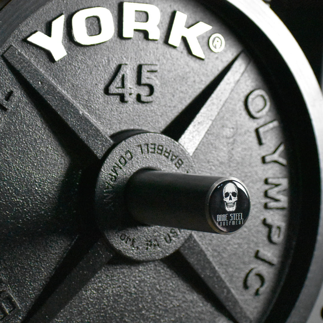 Close-up of a weight plate with 'Barbell Olympic' branding on a blurred background