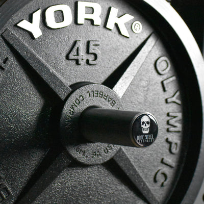 Close-up of a weight plate with 'Barbell Olympic' branding on a blurred background