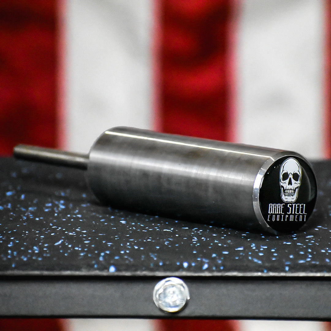 Metal cylindrical object with a skull logo on a black surface with an American flag in the background