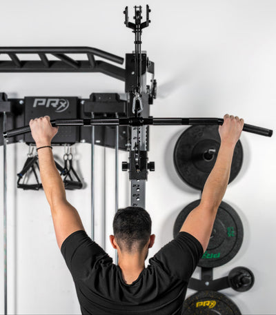 Person using a pull-up bar on a PRx fitness system against a white wall.